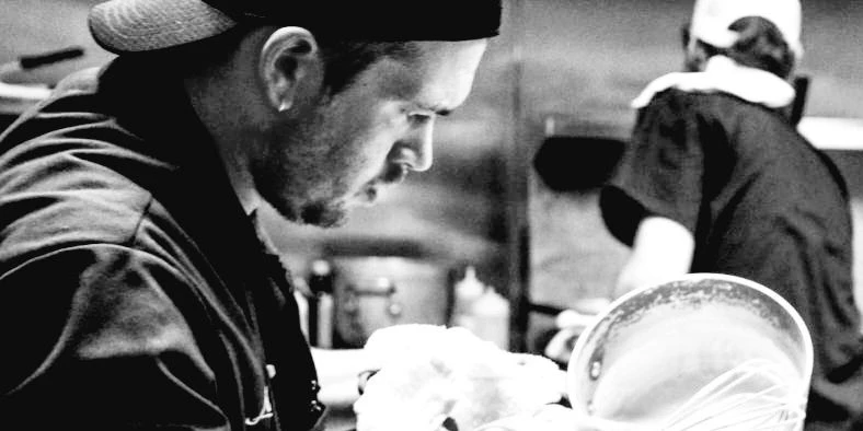 Chef Matt Scitney plating on the pass in a working kitchen
