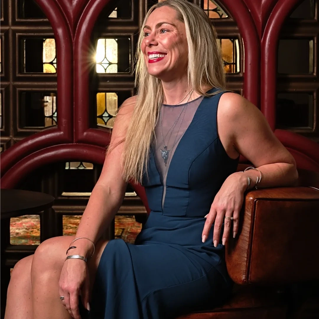 Kristen Carlson seated beneath the oxblood arches and stained glass of The Wine Grotto